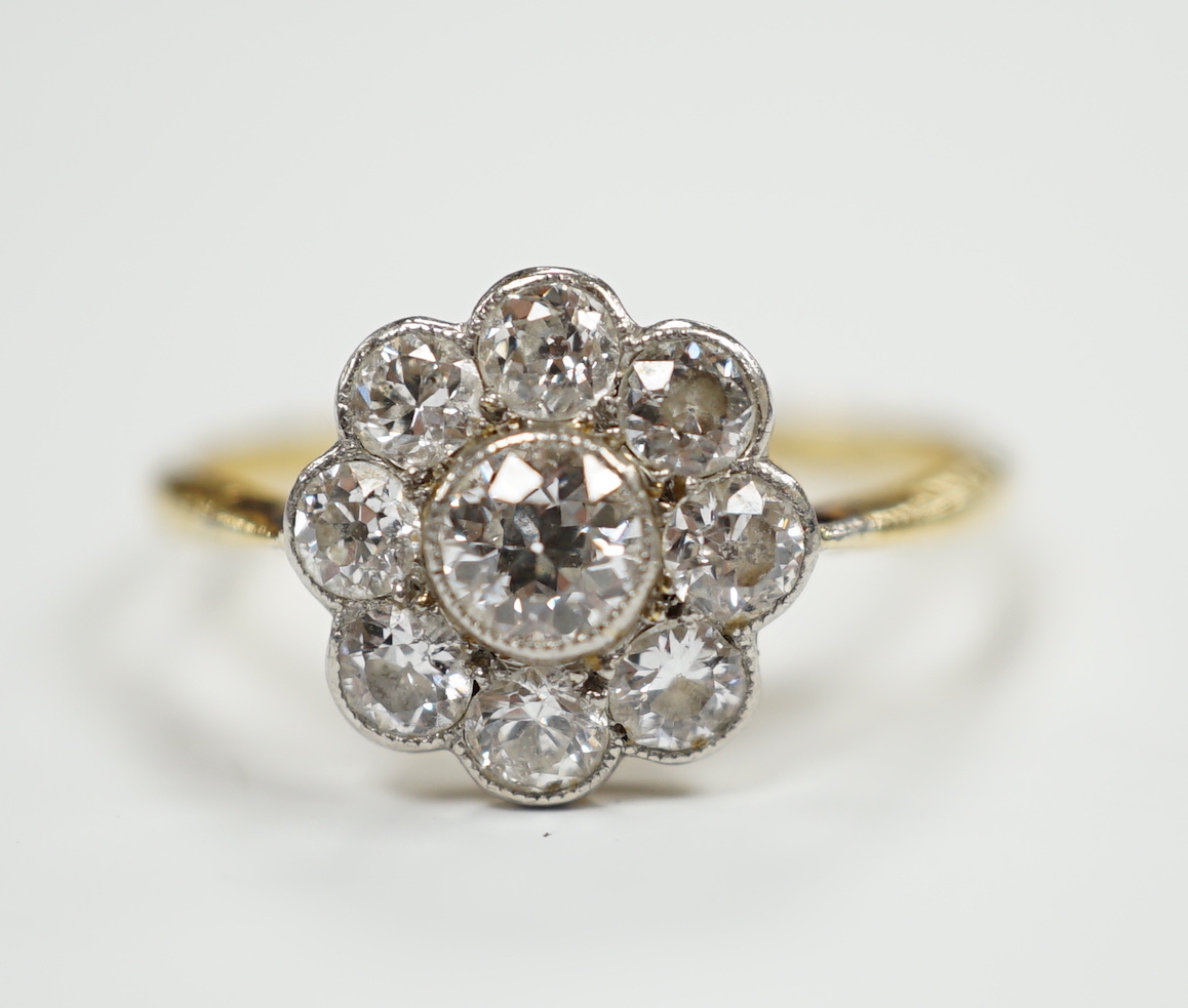 A 1930's/1940's 18ct and nine stone millegrain set diamond set flower head cluster ring, size P, gross weight 2.4 grams.